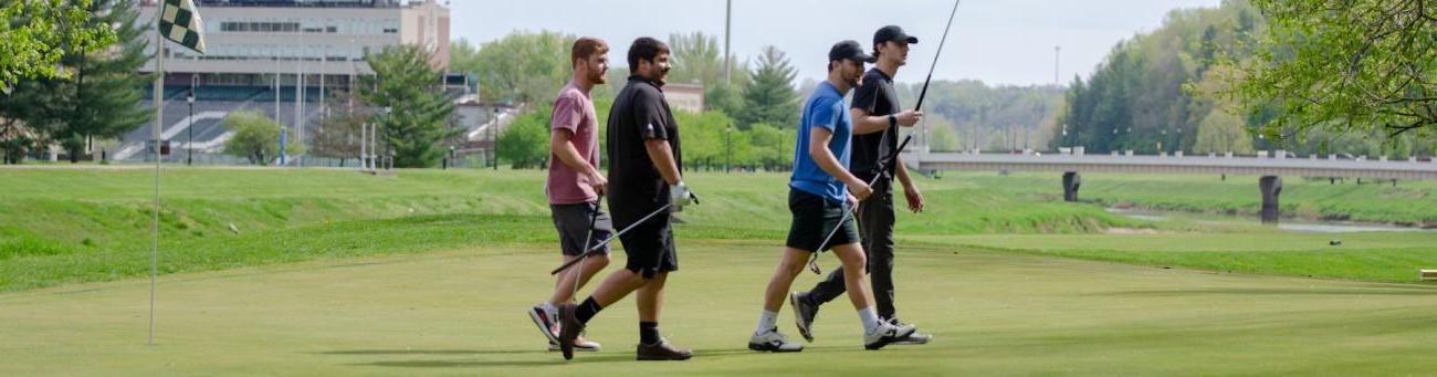 Players walk on the golf course green
