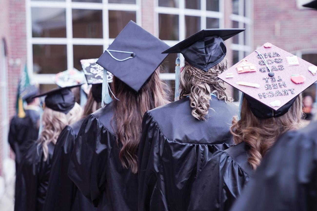 photo of graduates, back of several caps in a crowd